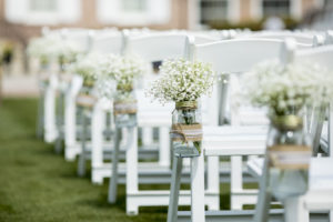 Mason jar with flowers hanging from chair for wedding